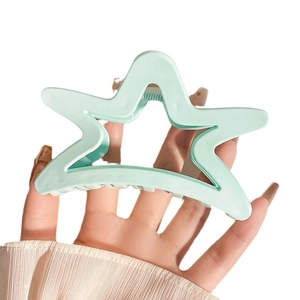 French style cream blue star-shaped hair claw clip held by hand against white background