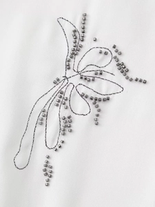 Detail of butterfly beadwork embroidery with silver beads and black thread on fabric