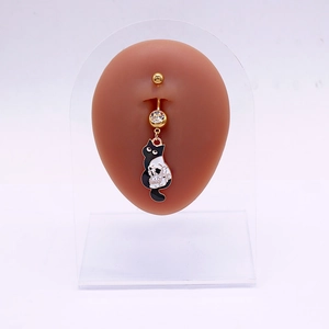 Détail du piercing nombril doré avec gemme, pendentif chat noir et tête de mort