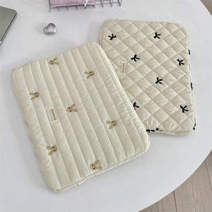 Close-up of quilted cream laptop sleeve with cute rabbit and bow embroidery detailing