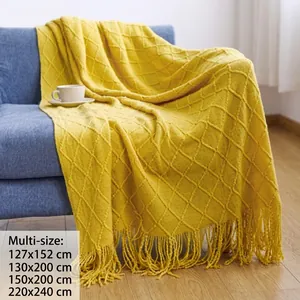Close-up of bright yellow knitted blanket featuring diamond textures and fringe on sofa