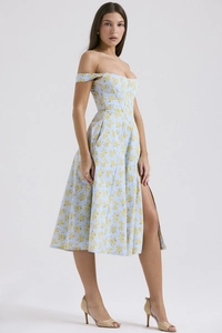 Detail view of the high side slit on a light blue floral midi dress with yellow patterns