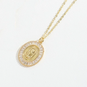 Detailed view of gold oval Virgin Mary pendant with baguette-cut cubic zirconia frame