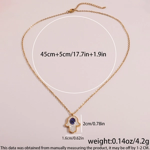 Golden Hamsa Hand necklace with blue stone and crystals on minimalist background