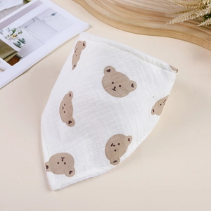 Detail of white cotton muslin baby bandana bib with cute brown bear prints and soft texture