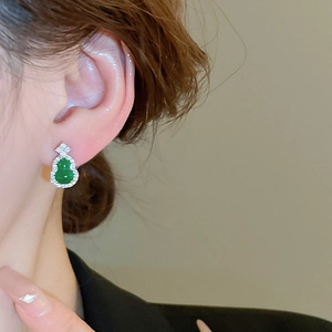 Close-up of emerald green gourd stud earrings with crystals on female model