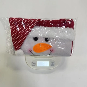 Detail showing a snowman Christmas gift bag on a digital scale weighing 91.7 grams