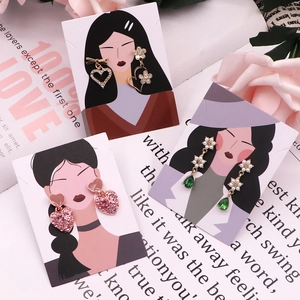 Three pairs of elegant heart and floral drop earrings presented on creative model cards