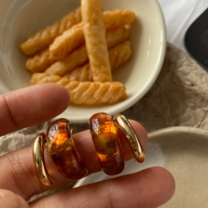Detailed macro view of vintage resin C-shape earring with amber texture and gold finish