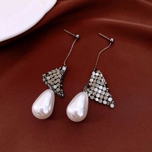 Close-up of 18k gold plated drop pearl earrings on luxurious dark silk fabric background