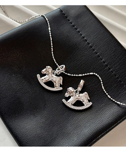 Macro detail of silver rocking horse pendants with textured finish on black leather