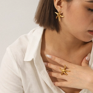 Detail of gold starfish ring and earring set on model with minimalist beach style