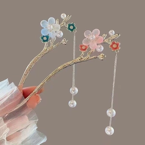 Detail of Chinese tassel hairpins with magnolia flowers and pearls held in lace hand