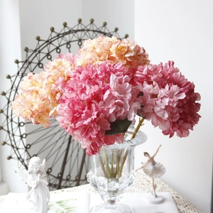 Close-up of pink and orange retro silk hydrangeas in a glass vase with home decor