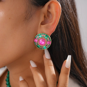 Détail macro de boucles d'oreilles dorées vintage avec cristaux colorés et pierre rose