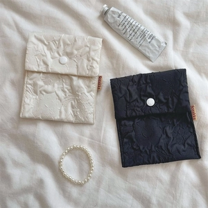 Detail of floral embossed sanitary storage pouch with secure snap closure and woven label
