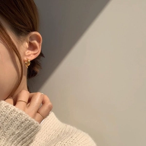 Polished 925 silver knot earrings and gold rings worn by model in minimalist lighting