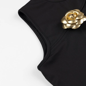 Detailed view of a black sleeveless top featuring a gold 3D leather camellia flower ornament