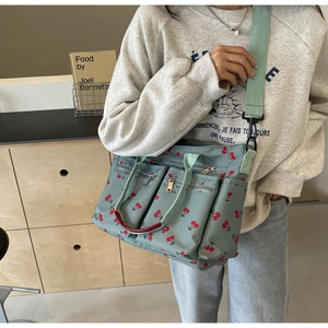 Detailed view of mint green cherry print tote bag with adjustable shoulder strap on model