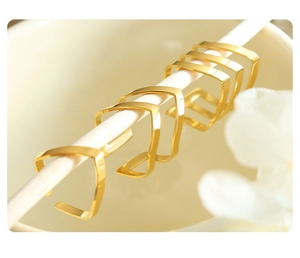 Detailed view of five minimalist geometric V-shaped gold rings on a white display stand