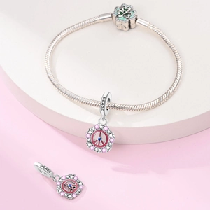 Macro shot of silver peace charm with pink stones and PEACE engraving on snake chain