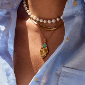 Layered gold titanium necklaces with white pearls and turquoise feather pendant on model
