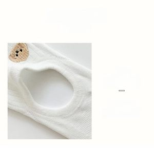 Close-up of white cotton ankle sock featuring brown bear embroidery and elastic ribbed cuff