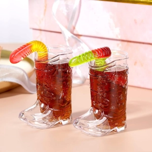 Pair of boot-shaped plastic shot glasses for cowboy themed parties with candy garnish