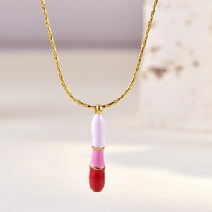 Close-up of pink and white enamel lipstick pendant on elegant gold chain necklace