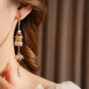 Détail de boucles d'oreilles bohèmes vintage dorées avec perles et cristaux portées