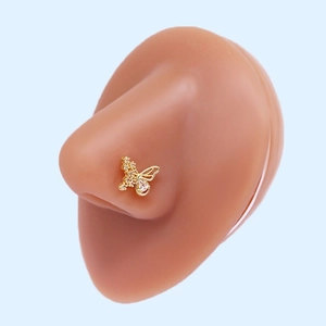 Macro shot of gold butterfly nose stud with cubic zirconia on silicone model