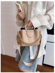 Detail of beige bucket bag with gold metal handle and bohemian print fabric strap