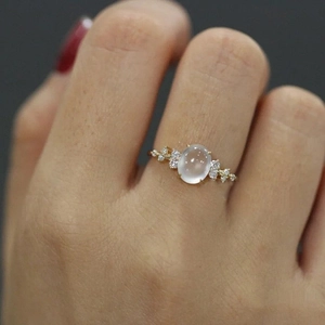Eleganter Goldring mit ovalem Mondstein und seitlichen Diamanten an der Hand