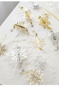 Detailed view of gold and silver metal snowflake and star ornaments on white snowy background