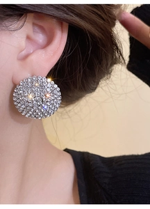 Close-up of sparkling silver round stud earrings with pave crystals worn by a model