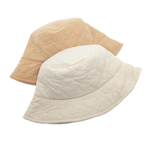 Detail of corduroy bucket hats with quilted heart patterns in khaki and beige tones