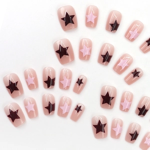 Short square press-on nails with star patterns in nude pink and black color blocking