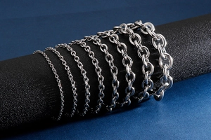 Detail showing various sizes of stainless steel O-link chains on a black cylinder