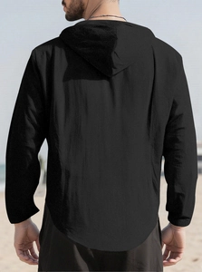 Detailed back view of a men's black hooded cotton shirt on a sandy beach