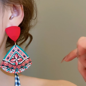 Close-up of geometric acrylic drop earrings with retro floral prints worn by a model