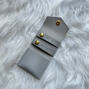 Macro view of light grey leather jewelry pouch with gold snap and stud earring holders