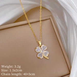Close-up of golden clover necklace featuring translucent white cat eye stone on box