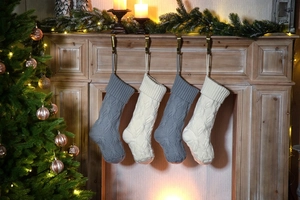 Detail of knitted Christmas stockings in grey and cream hanging on a wooden fireplace mantle