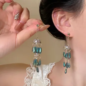 Detailed view of vintage silver earrings featuring teal crystal tassels on a model