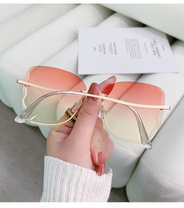 Detail of rimless butterfly sunglasses with orange gradient lenses and gold metal arms