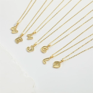 Gold letter pendant necklaces with honeycomb texture on minimalist chains in a neat row