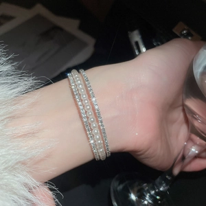 Close-up of elegant double-layer silver bracelet with white pearls and sparkling rhinestones