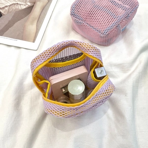 Macro view of purple mesh mini makeup bag with yellow zipper showing cosmetics inside