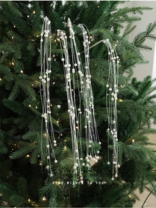 Gros plan d'une chaîne de perles blanches sur une branche de sapin de Noël décorative