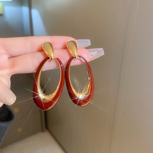 Close-up of vintage oval drop earrings featuring red oil-drip texture and gold-plated metal